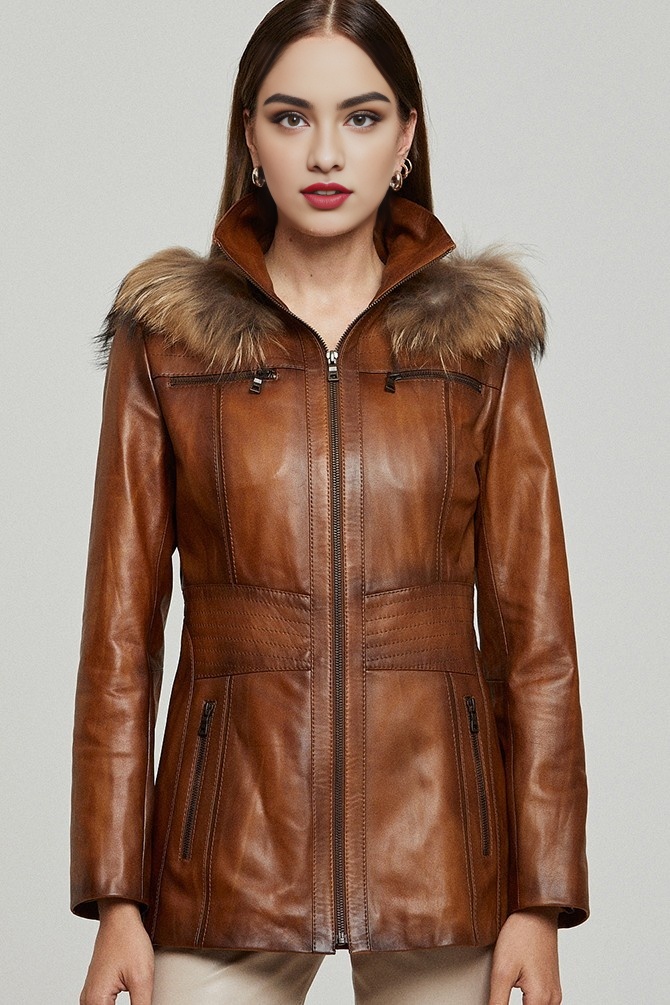 A stylish woman wearing a long brown leather coat paired with boots.