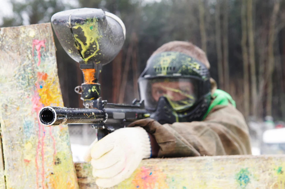 Paintball players wearing weather-appropriate uniforms in hot and cold conditions, showcasing breathable summer jerseys and insulated winter gear for performance and comfort